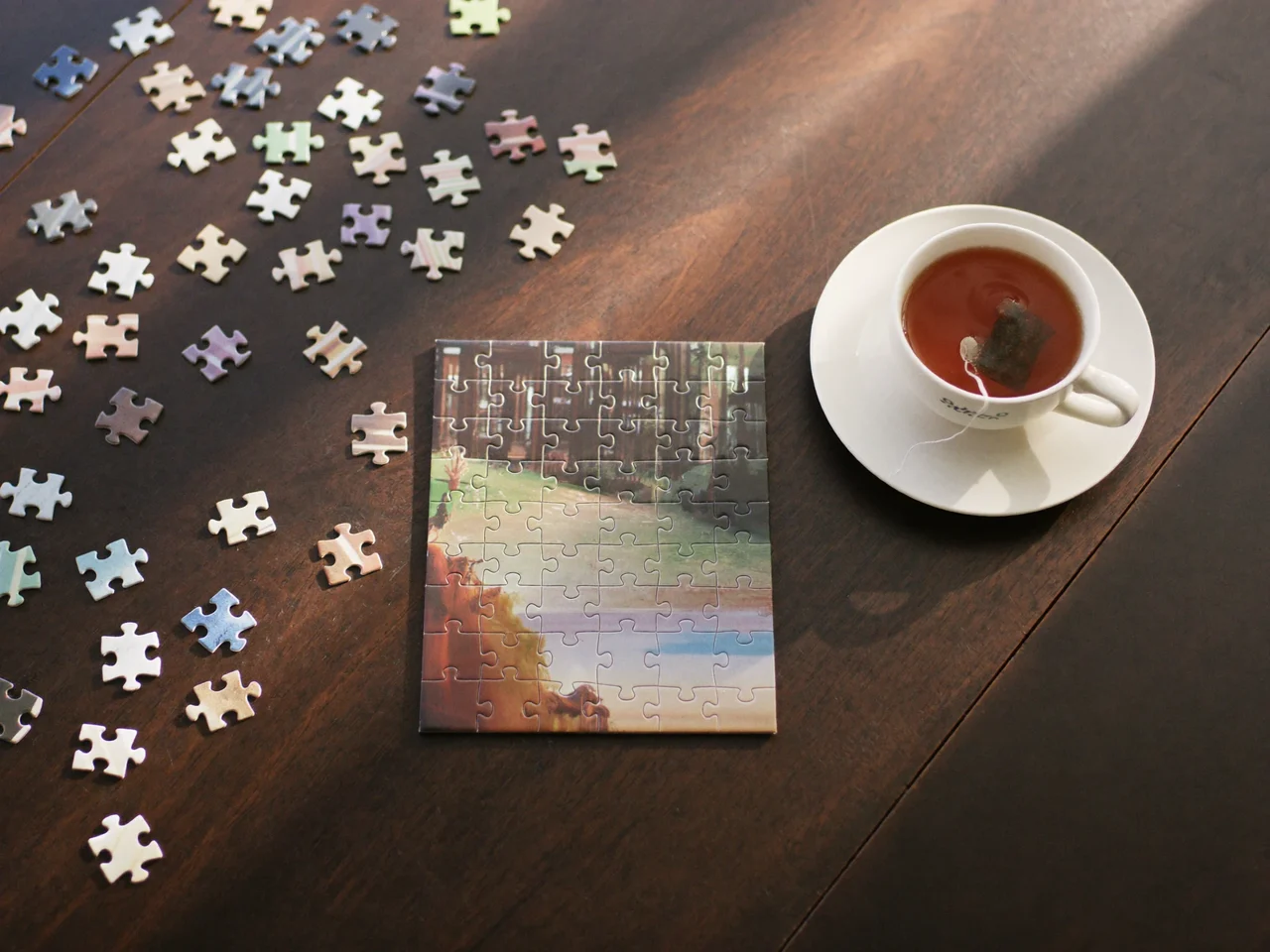 Puzzle clasic din carton asamblat parțial pe o masă din lemn închis la culoare