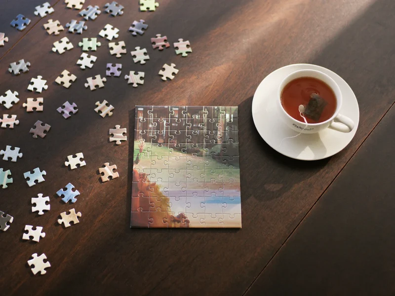 Puzzle clasic din carton asamblat parțial pe o masă din lemn închis la culoare